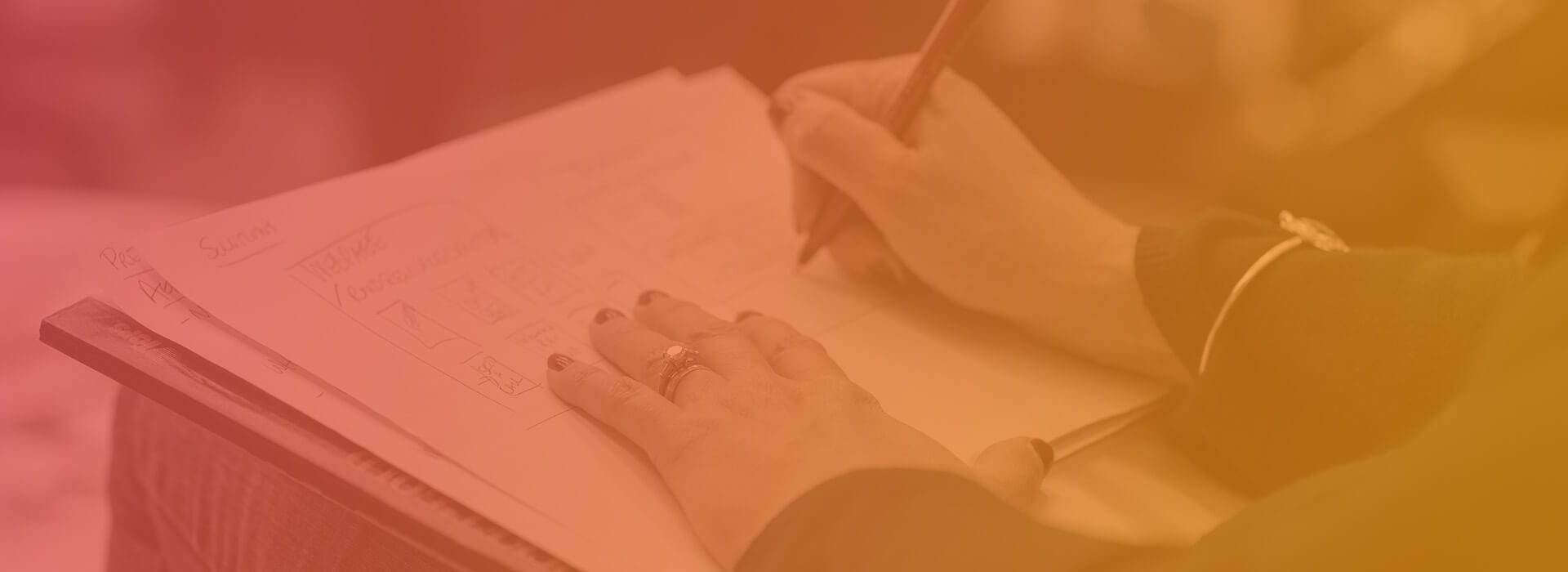 a person using a pen to sketch wireframes in a notebook